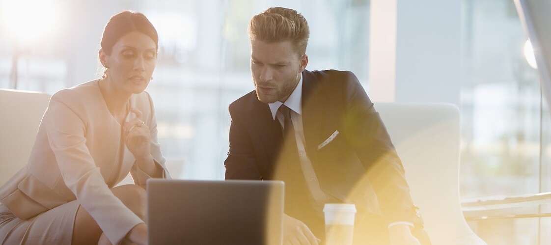 A woman and a man in business suits with laptops