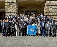 A large group of people pose for a photo in front of a large building