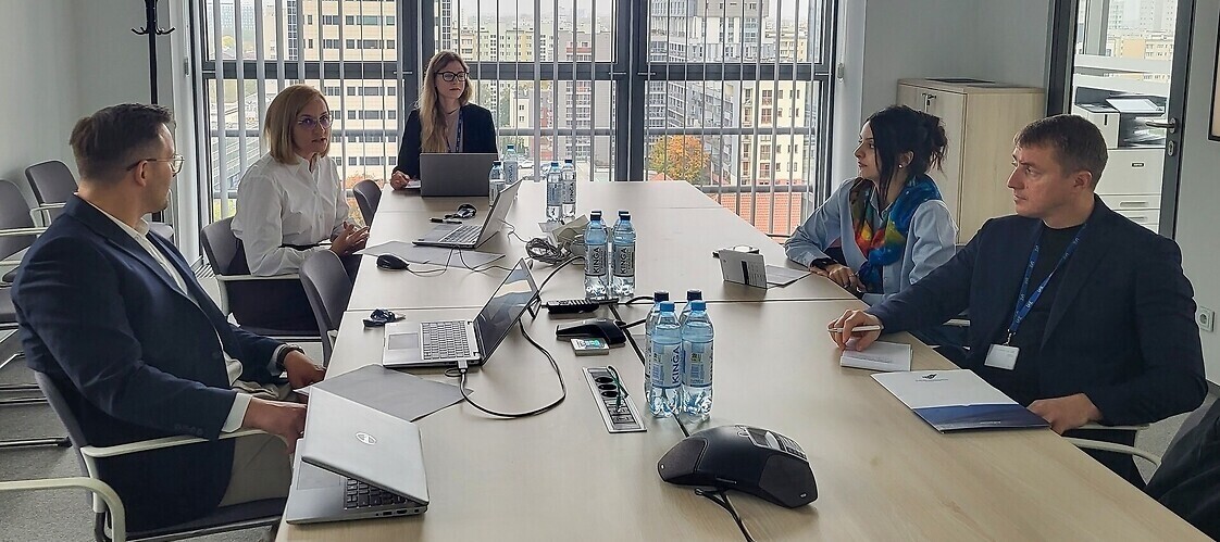A group of people are sitting at a table in a conference room