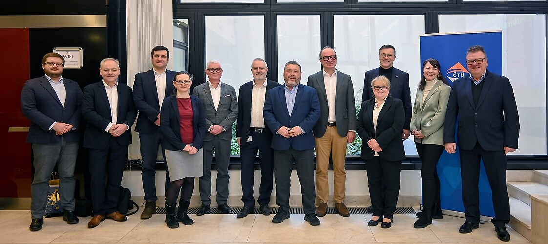 A group of people in business attire in an office space pose for a group photo