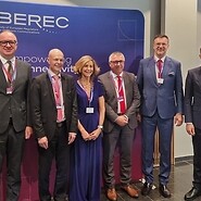 A group of people poses for a photo in front of a backdrop featuring the BEREC logo.