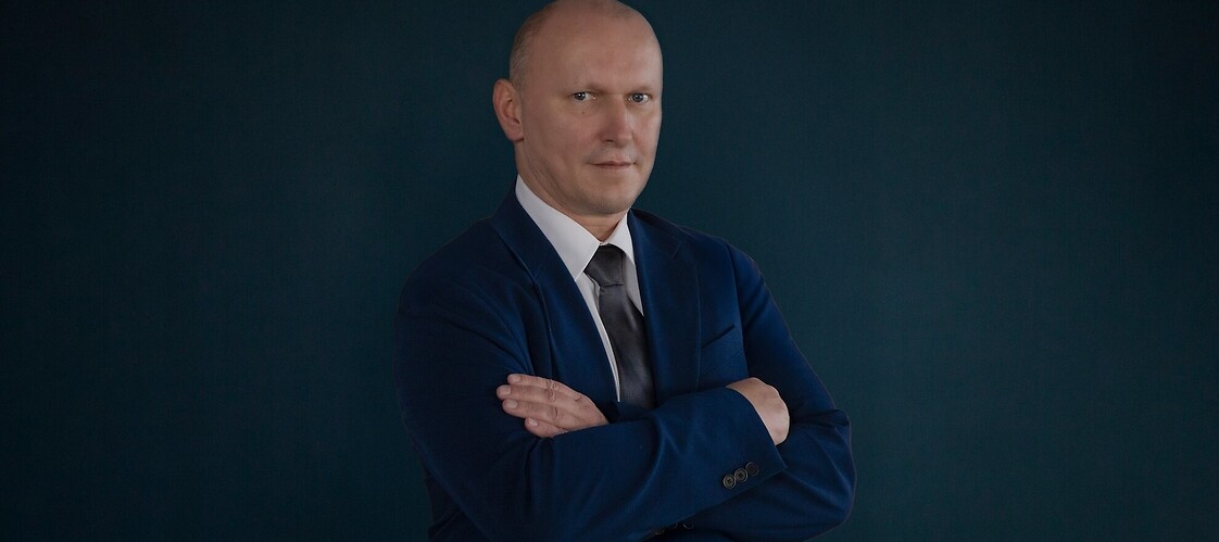 Męzczyzna w ciemnym garniturze na ciemnym jednolitym tle