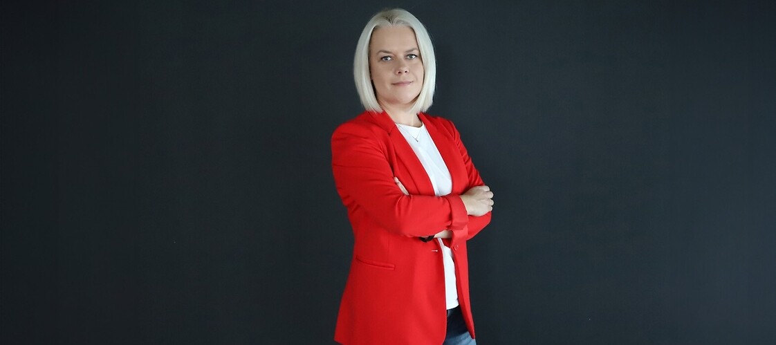 Kobieta w czerwonym żakiecie i białej bluzce na ciemnym jednolitym tle