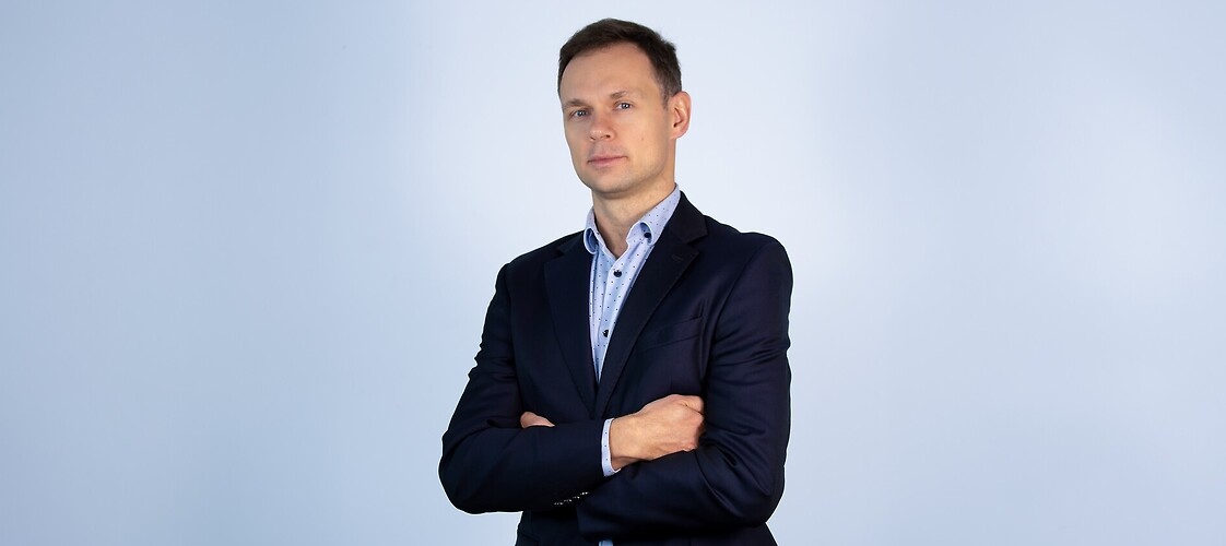 Męzczyzna w marynarce i jasnej koszuli na jasnym tle