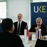 Mężczyźni przy stole na tle logotypu UKE