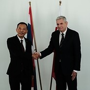 Dwóch mężczyzn na tle białej ściany i flag Polski i Tajlandii