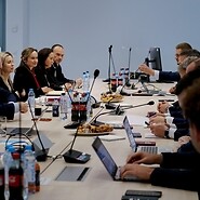 Grupa osób po obu stronach stołu konferencyjnego