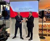 Dwóch mężczyzn w garniturach na stoisku targowym, w tle biało-czerwona flaga ...