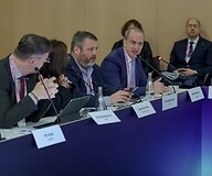 Grupa osób w garniturach za stołem konferencyjnym