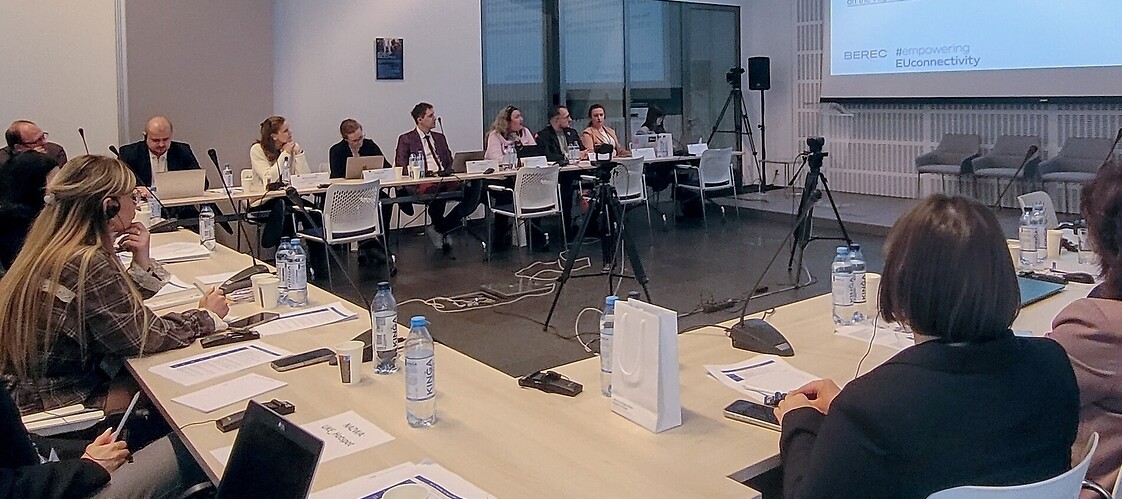 Grupa osób za stołami w sali konferencyjnej