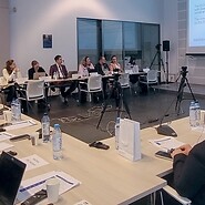 Grupa osób za stołami w sali konferencyjnej