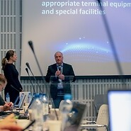 Mężczyzna przed ekranem w sali konferencyjnej, na pierwszym planie rozmyte ...