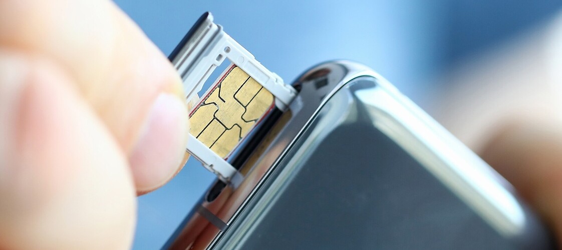 Palce trzymajace kartę sim wkładaną do gniazda w smartfonie