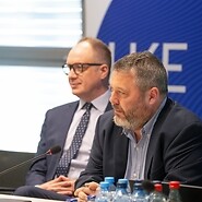 Dwóch męzczyzn za stołem konferencyjnym, za nimi banner z logotypem UKE
