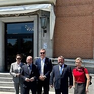 Pięc osób pozuje w szeregu do zdjęcia przed budynkiem